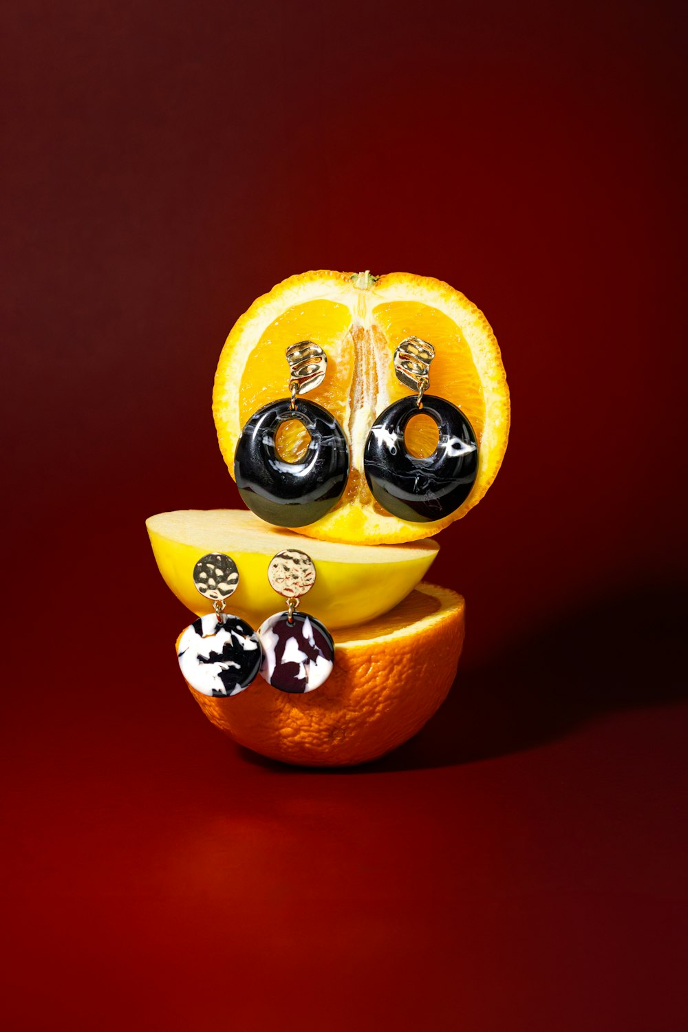 an orange with a pair of black and white earrings sitting on top of it