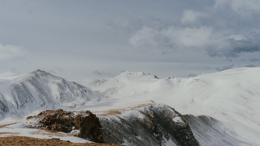 a mountain range covered in snow under a cloudy sky