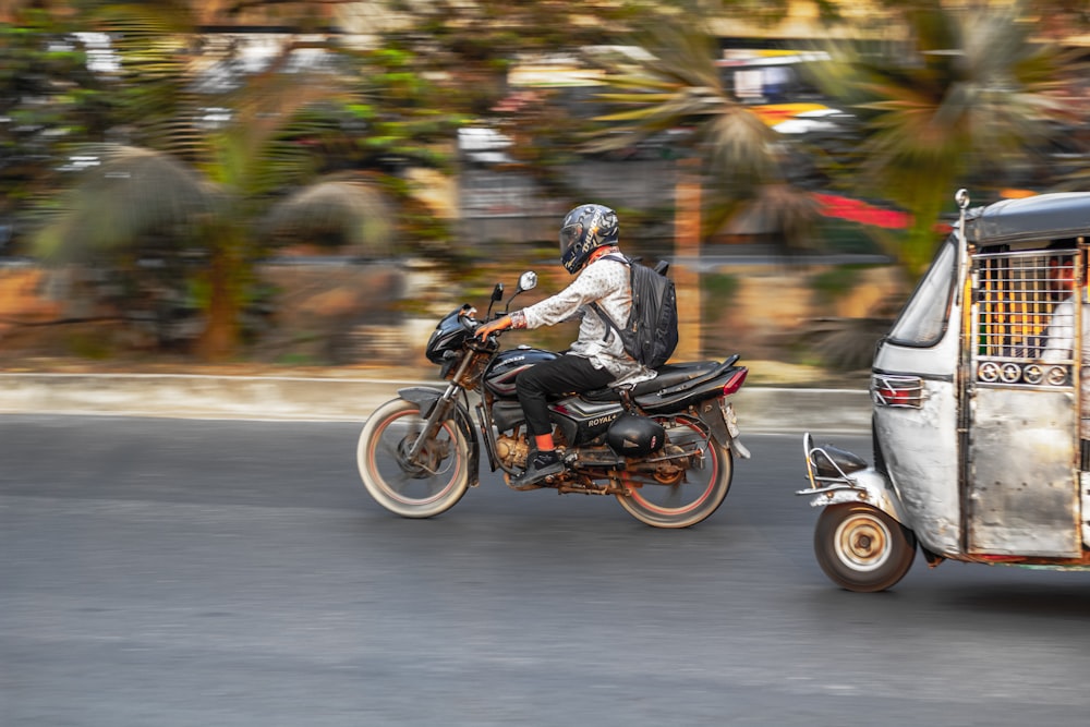 a man riding on the back of a motorcycle next to a small truck