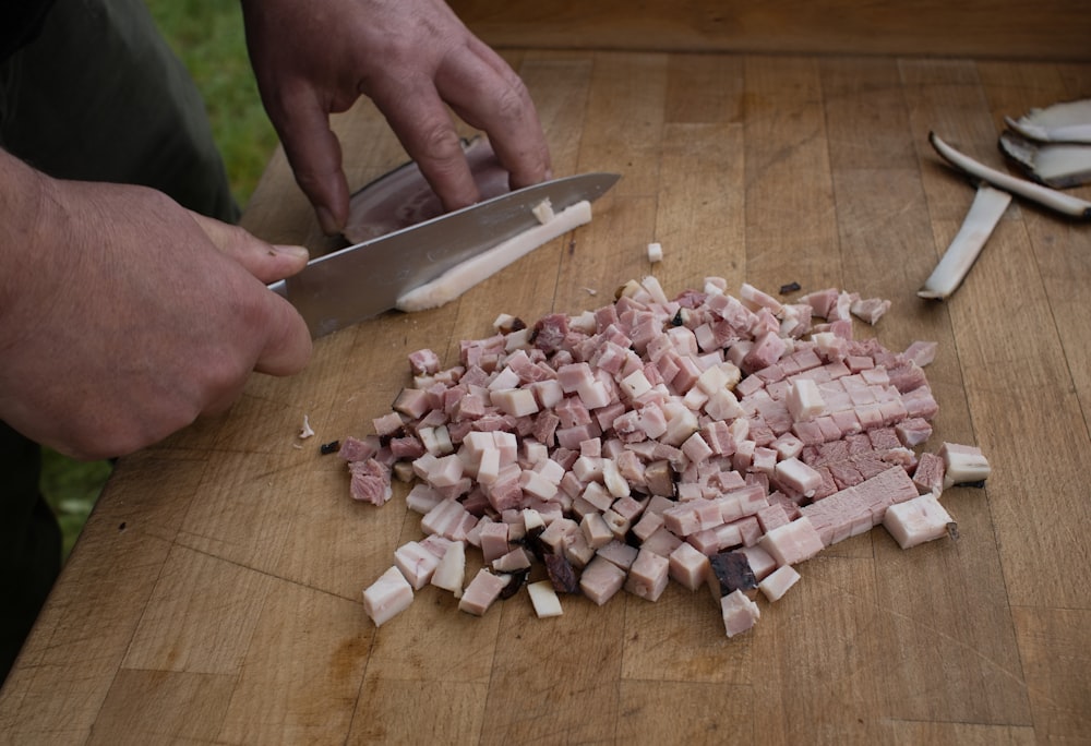 a person cutting up food on top of a wooden cutting board