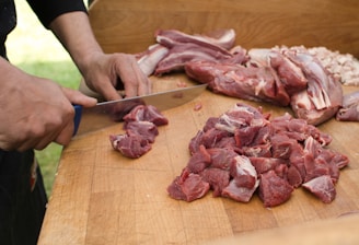 a person cutting up meat on a cutting board