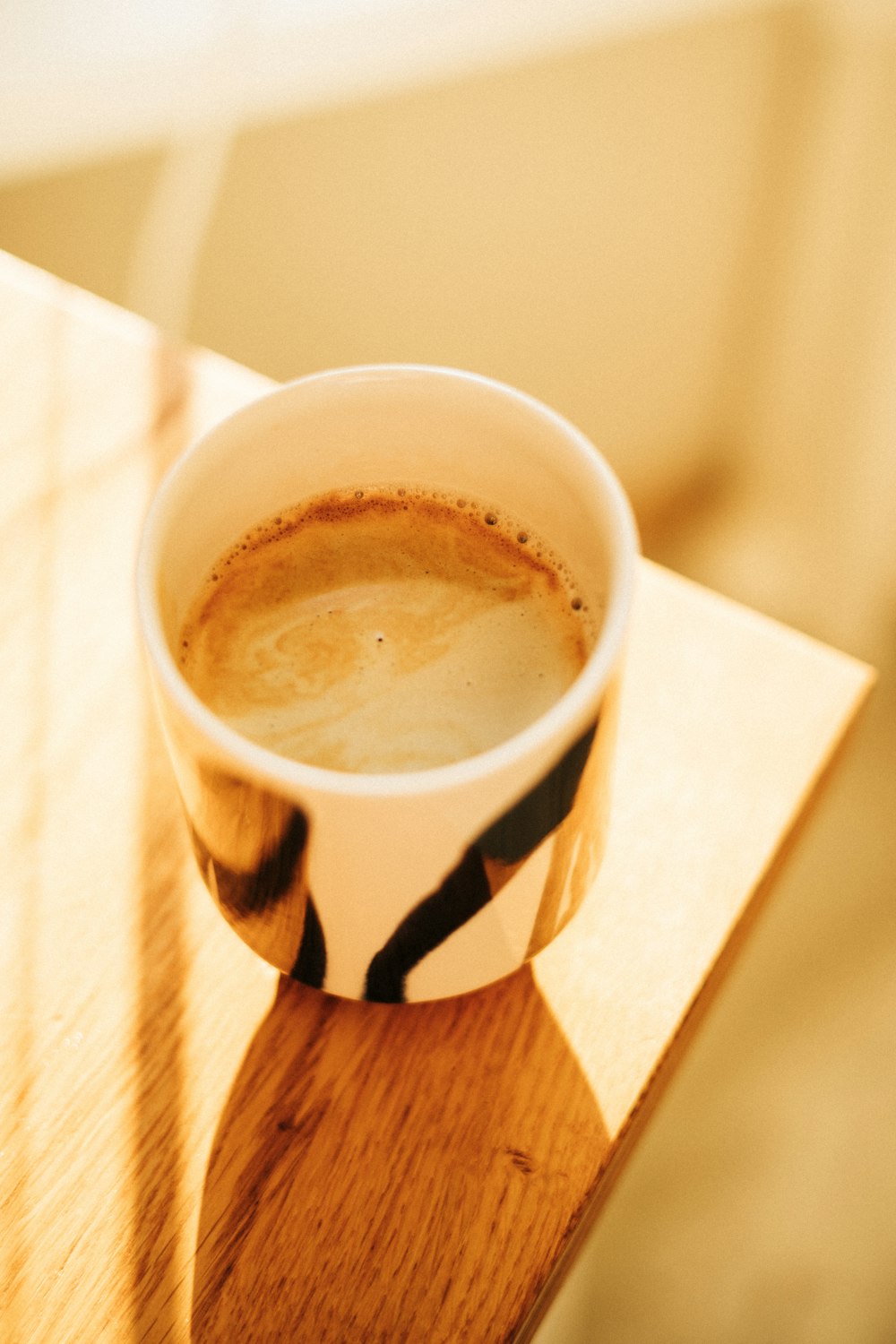 uma xícara de café sentada em cima de uma mesa de madeira