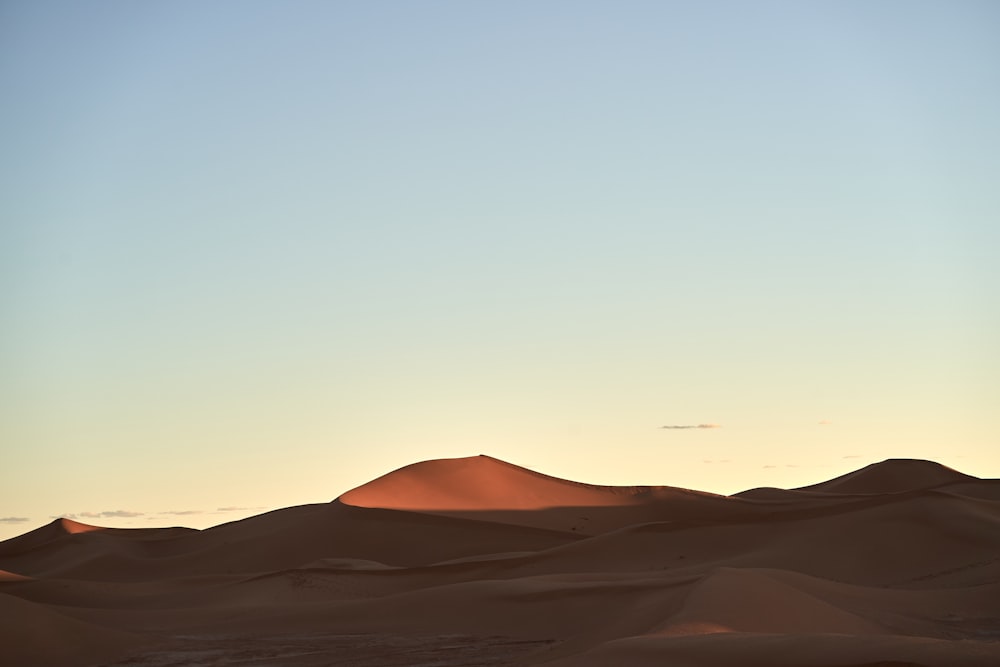 the sun is setting in the distance over the sand dunes
