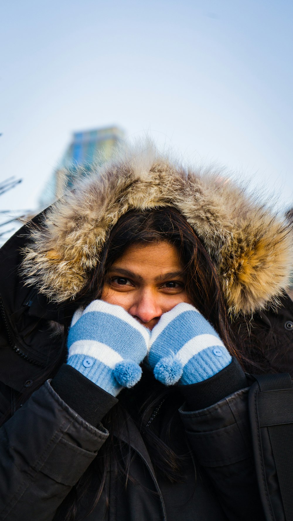 a woman in a parka covers her face with her hands