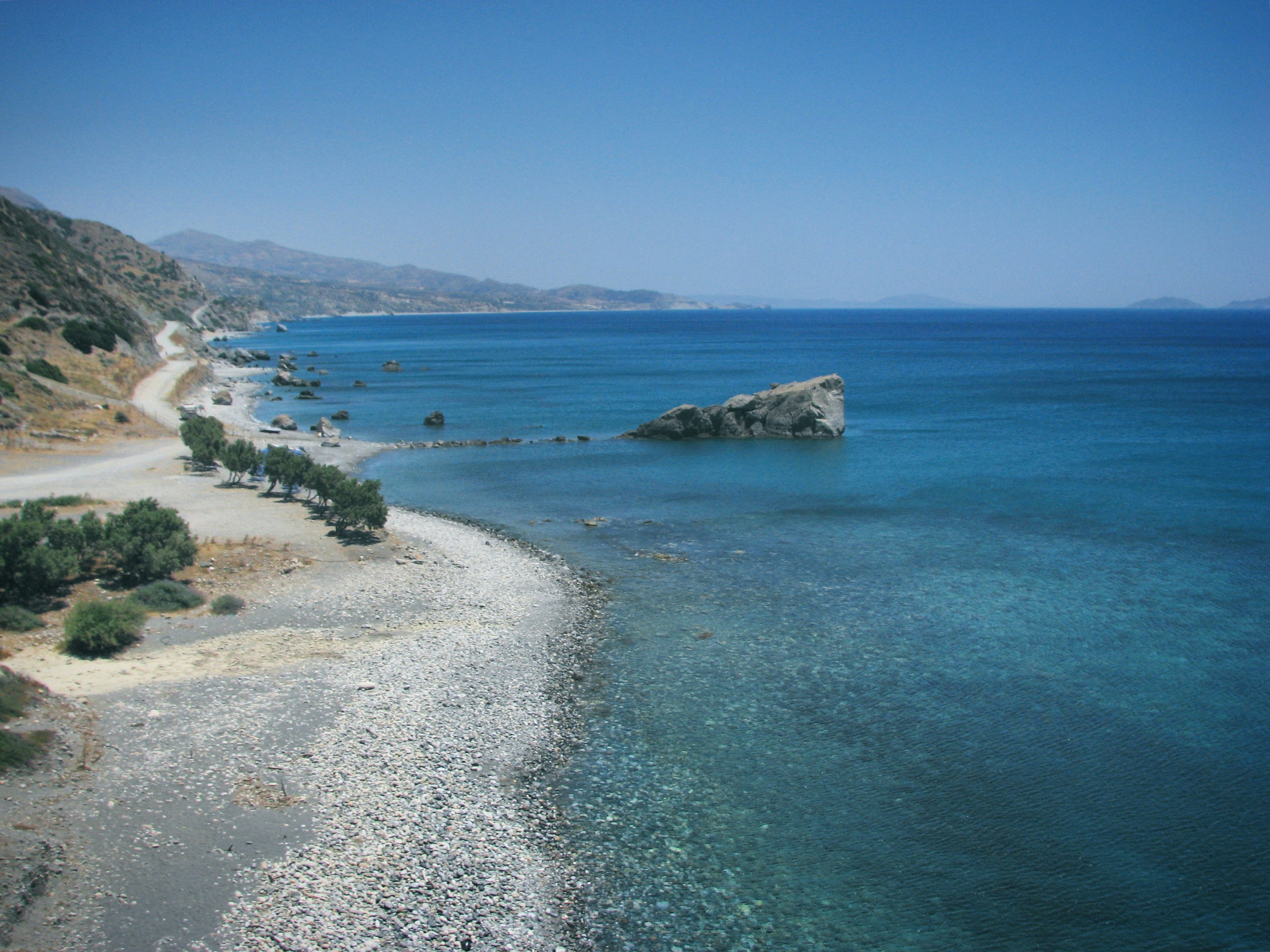 a view of a beach with a rock outcropping in the water, View of the Mediterranean Sea and the beach near Preveli, Crete, Greece, May 2008