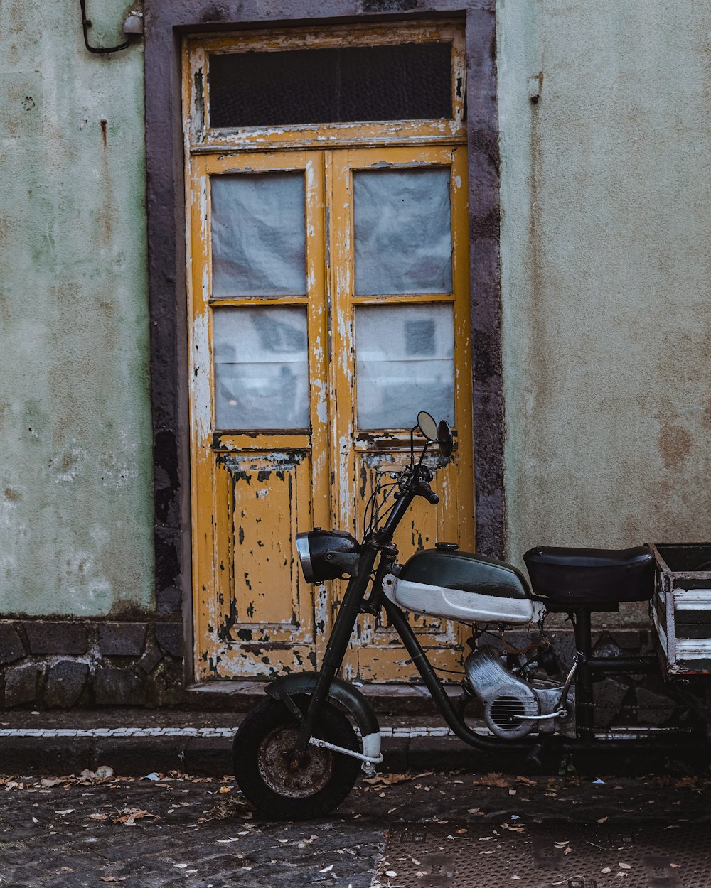 a moped parked in front of a yellow door