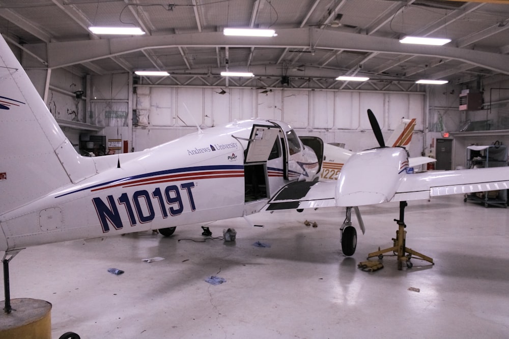 a small white airplane parked inside of a hangar