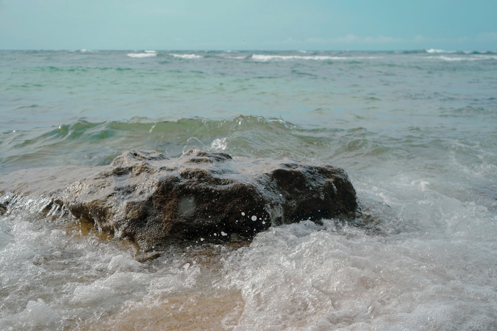 a rock sticking out of the ocean water