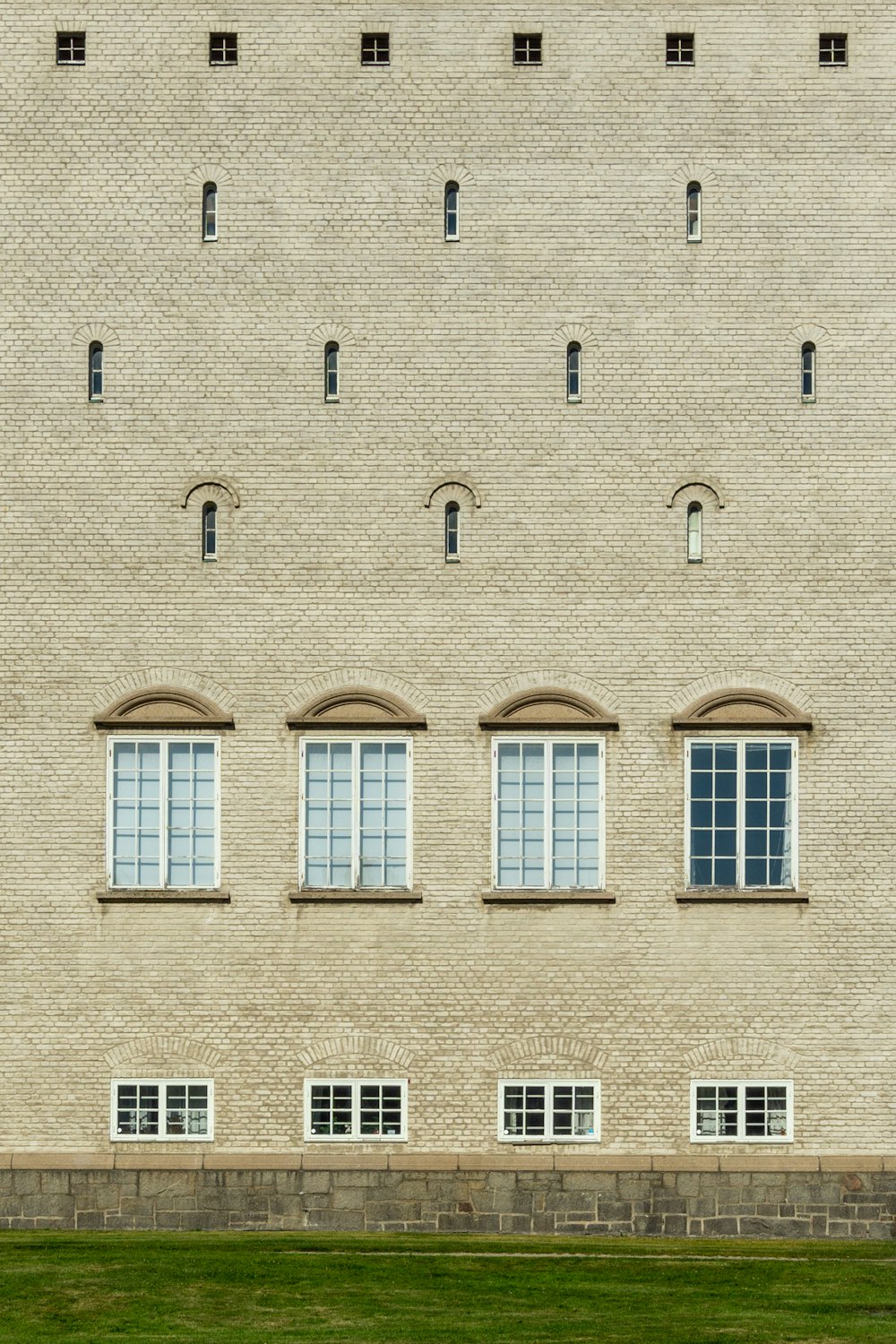 a large brick building with four windows and a green lawn in front of it