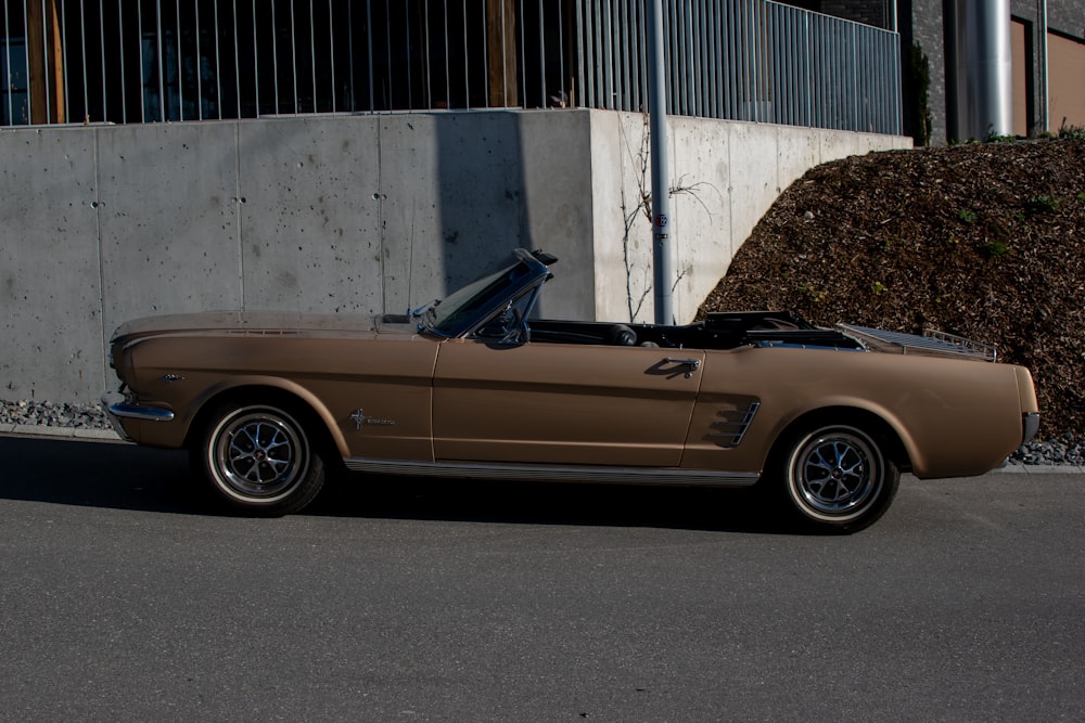 a brown mustang convertible parked in front of a building