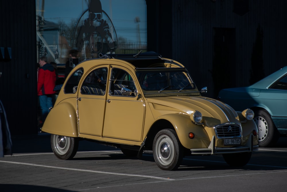 an old yellow car parked in a parking lot