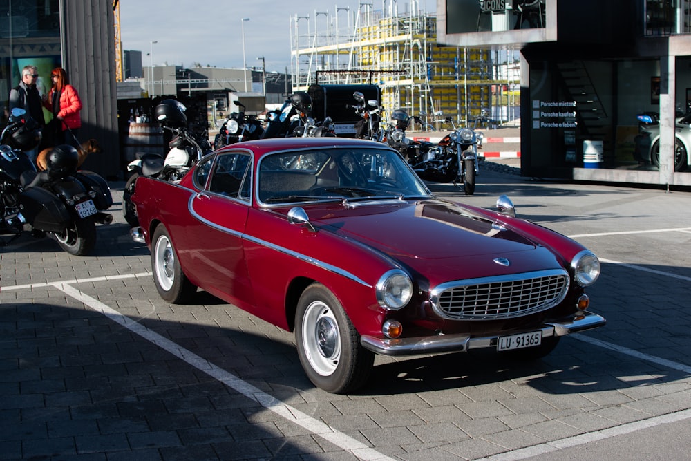 a red classic car parked in a parking lot