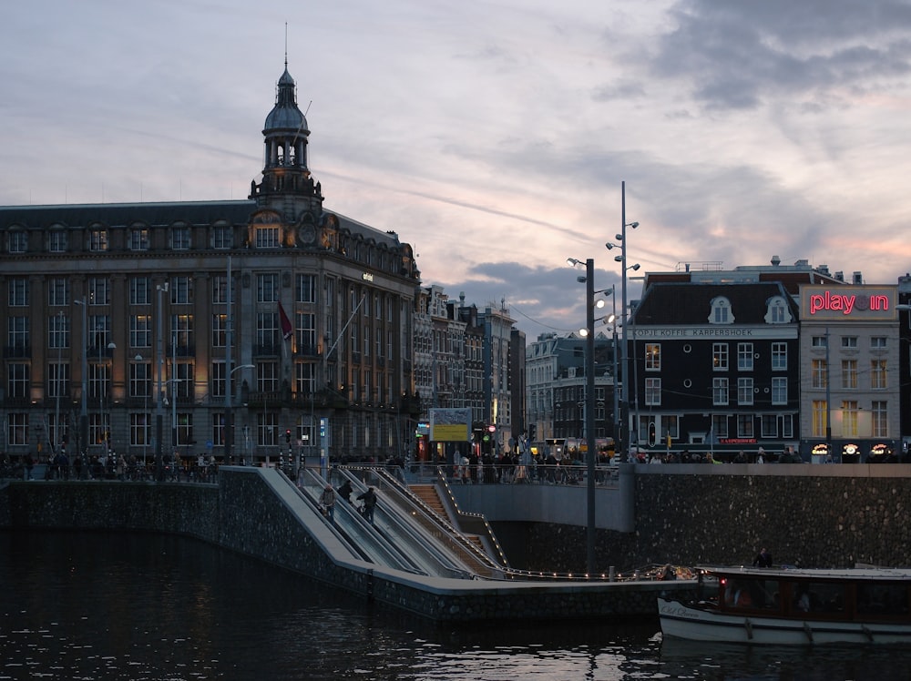 a boat floating down a river next to a tall building