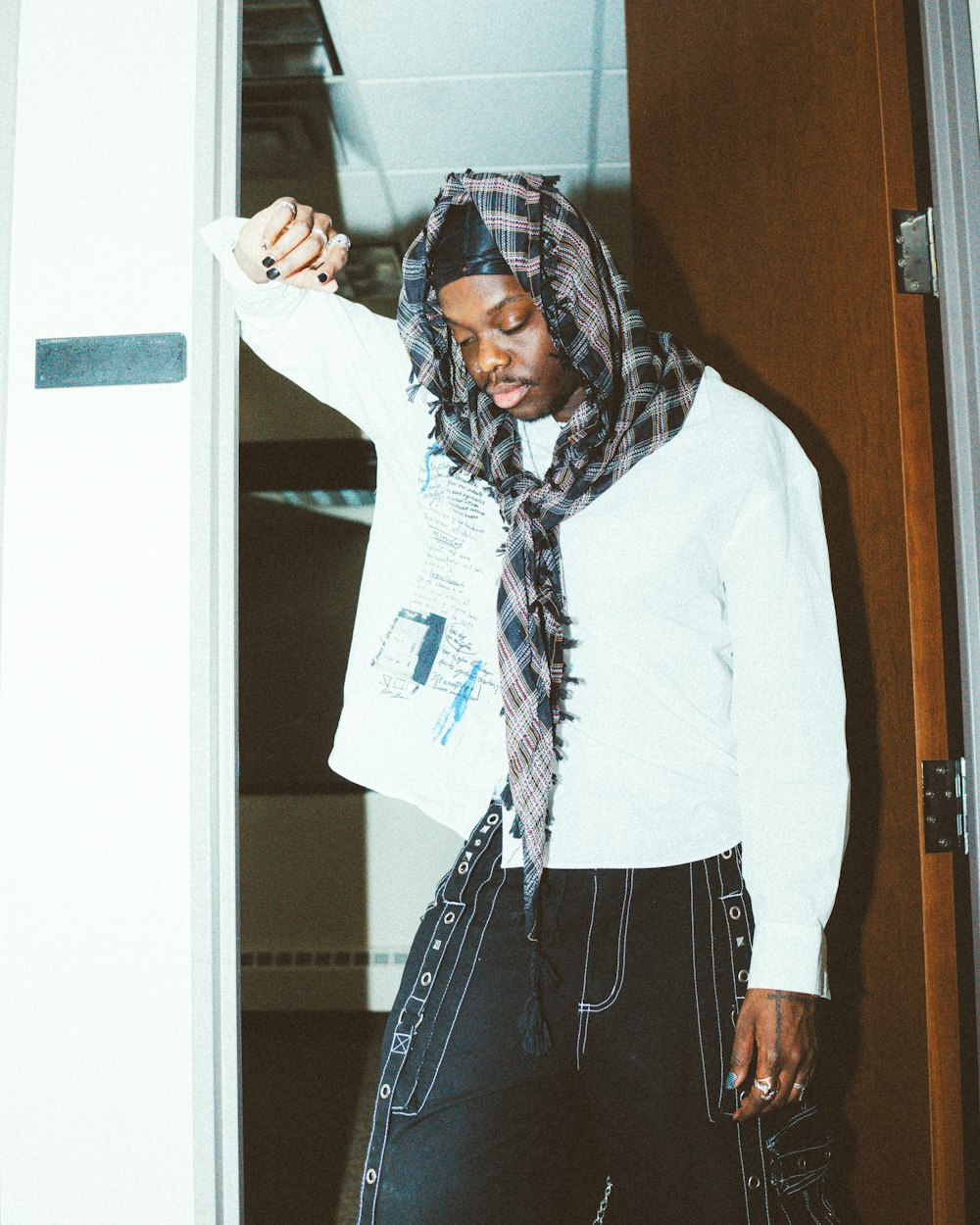 a woman standing in a doorway with a scarf around her head