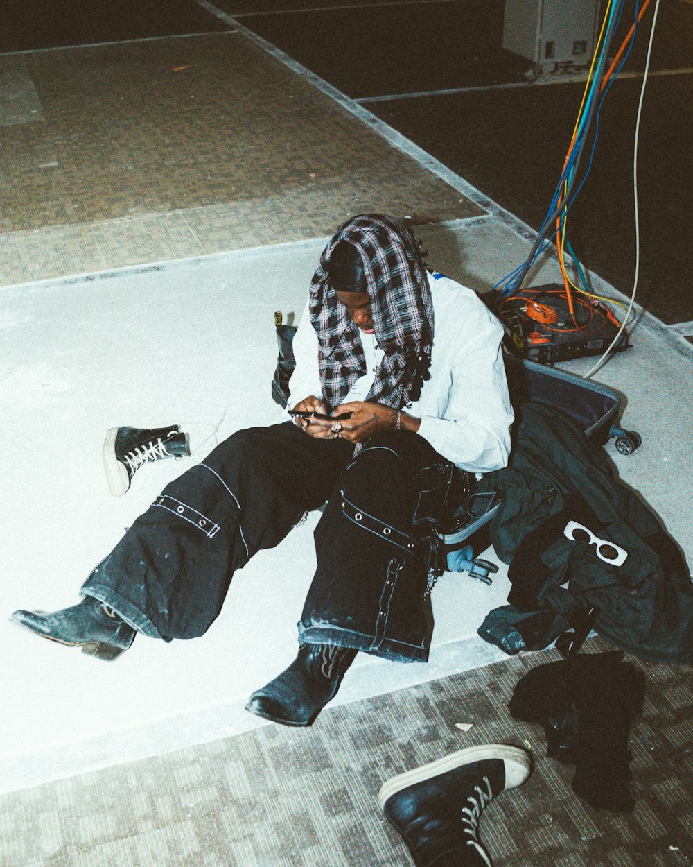 a man sitting on the ground looking at his cell phone