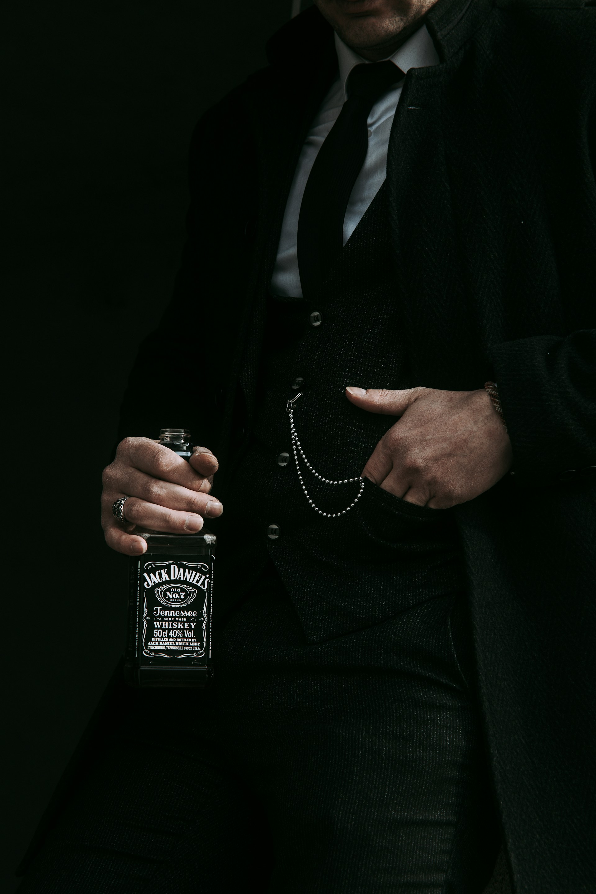 a man in a suit holding a bottle of whiskey