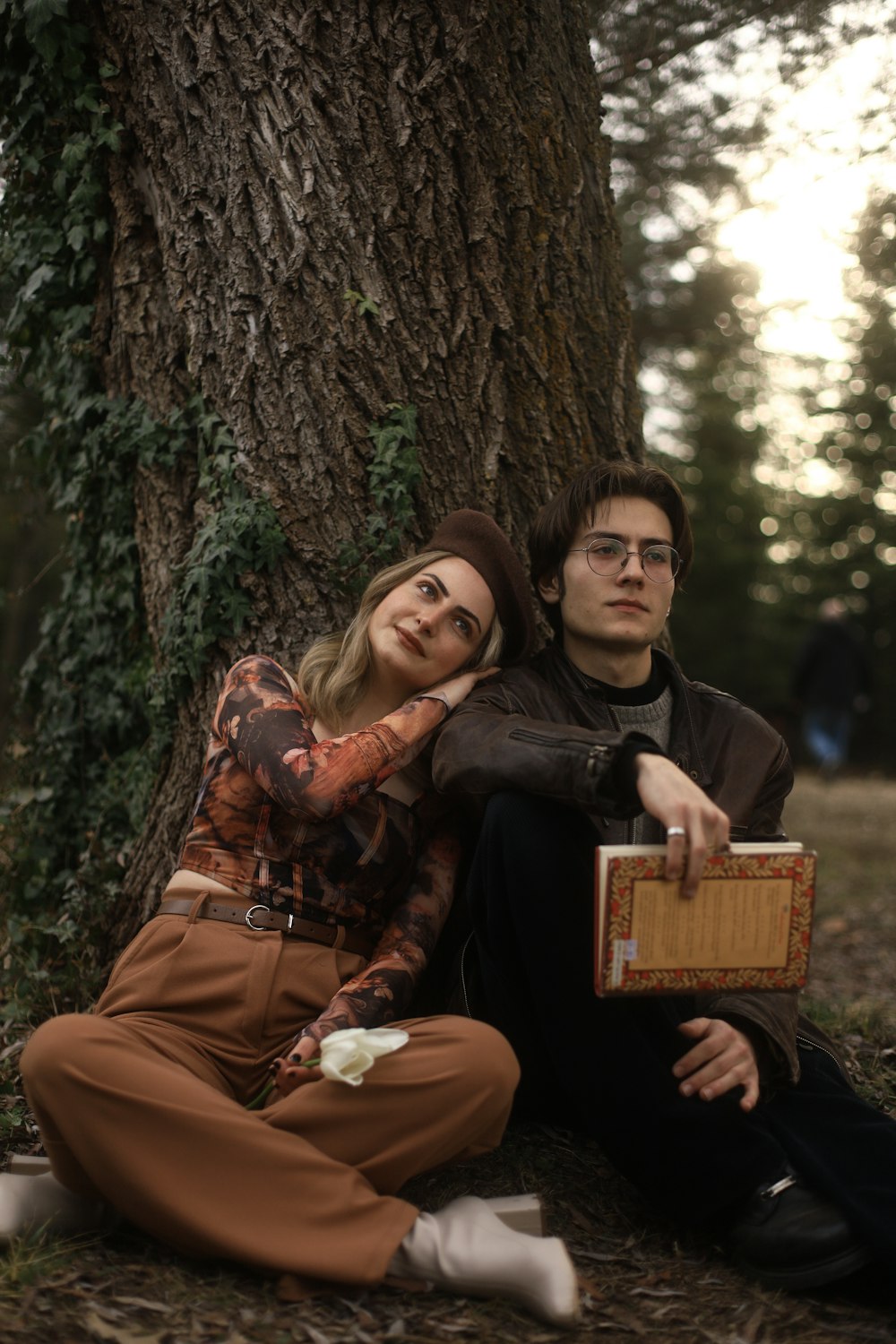 a man and a woman sitting next to a tree