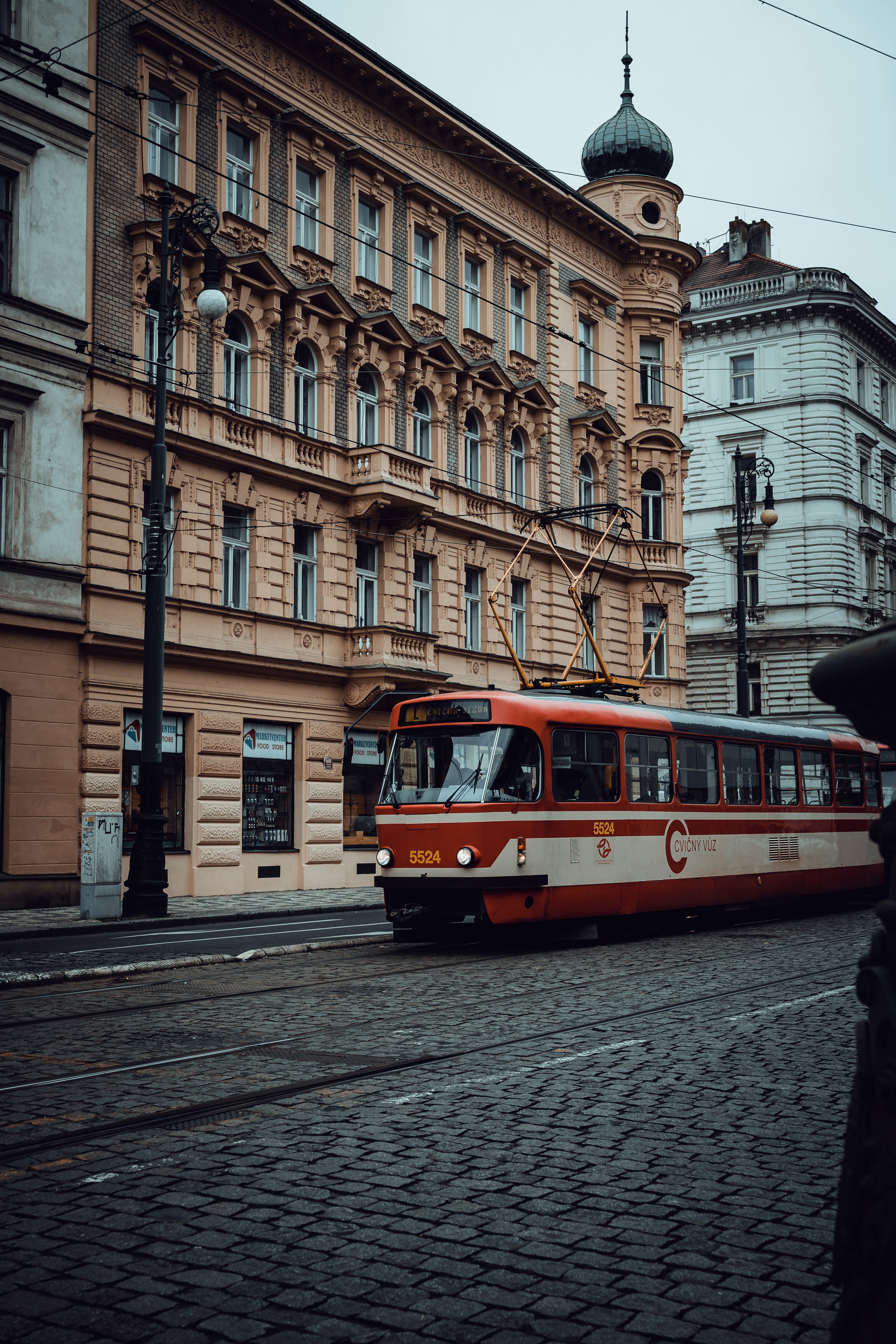 a red and white train traveling down a street next to tall buildings