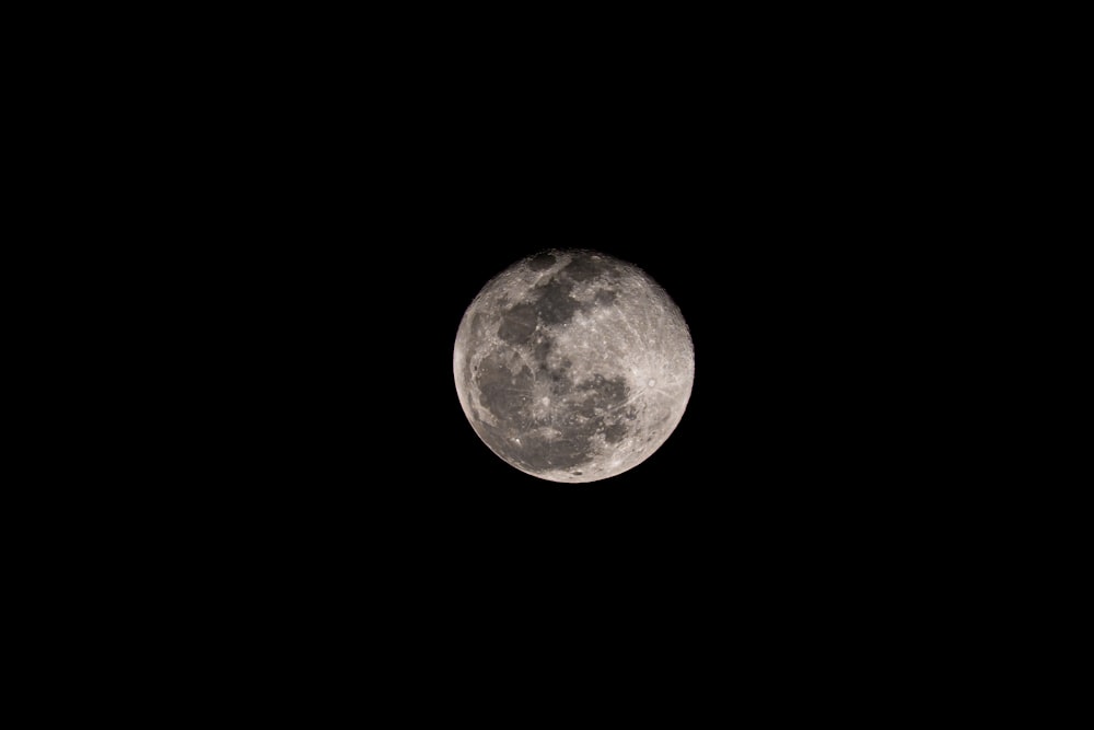 a full moon is seen in the dark sky