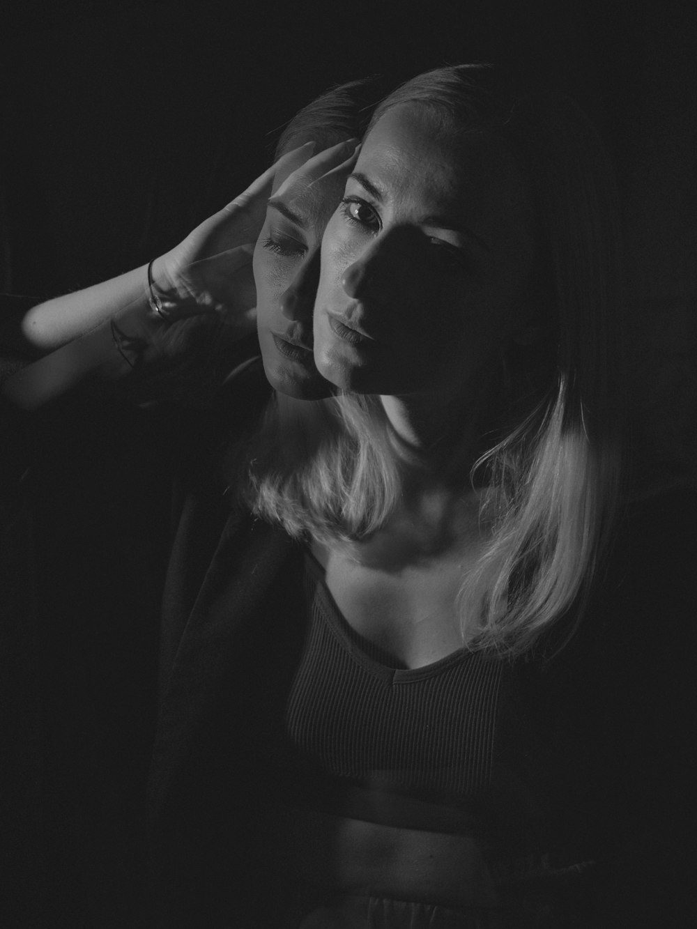 a black and white photo of a woman holding her hair