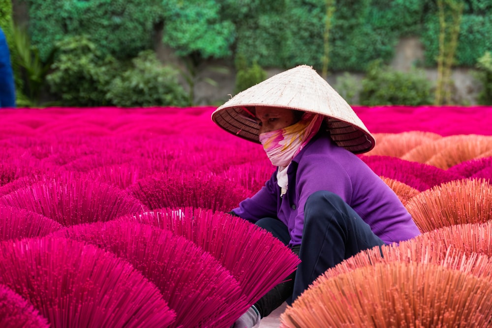 una mujer arrodillada en un campo de flores púrpuras