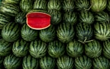 a large pile of watermelon with a piece of watermelon on top