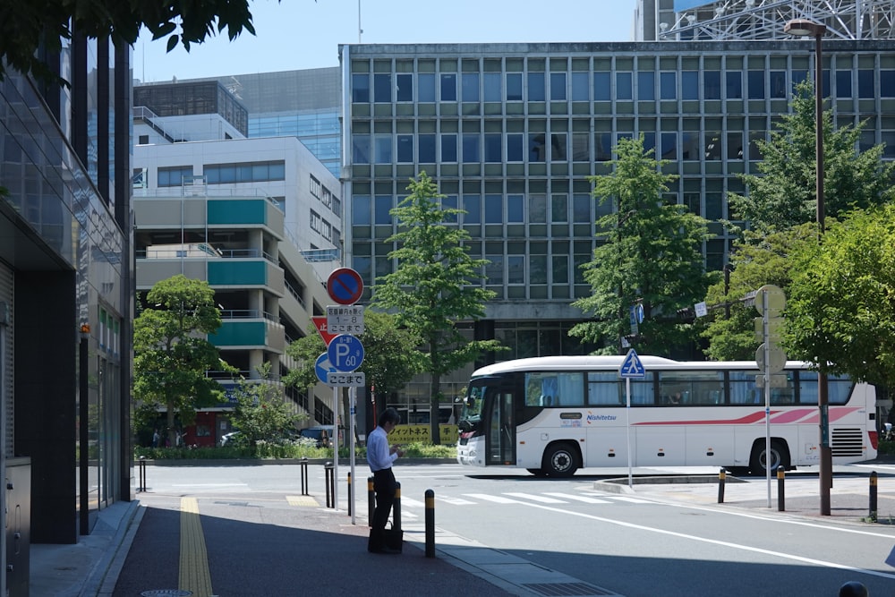 a white bus driving down a street next to tall buildings