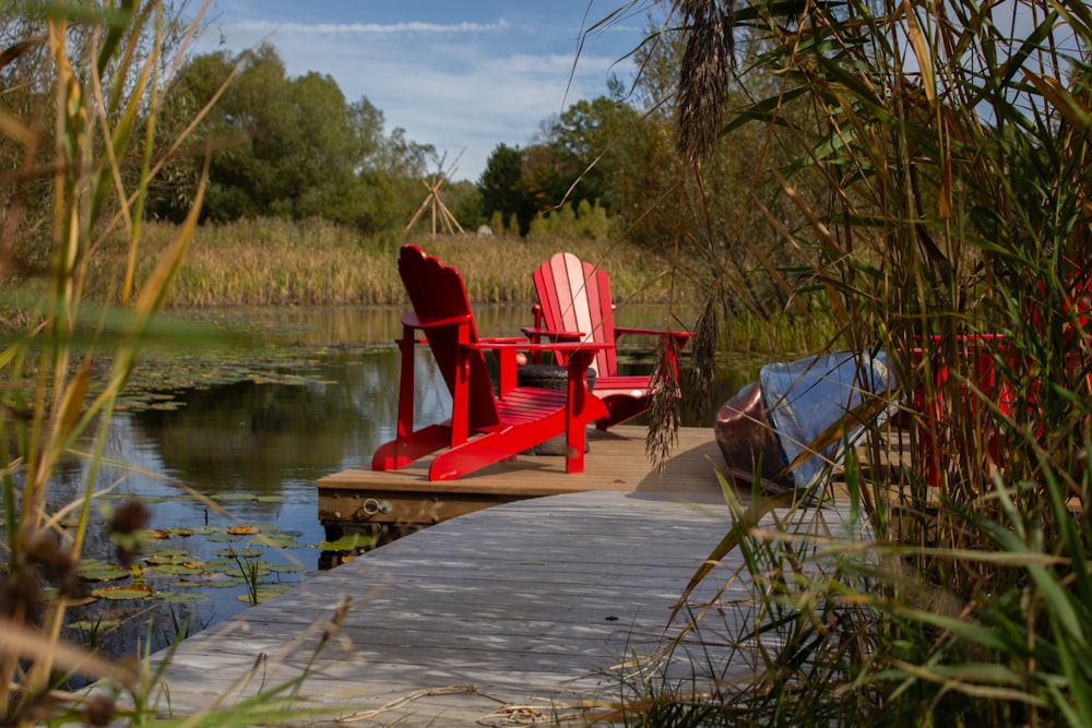 a red chair sitting on a dock next to a body of water