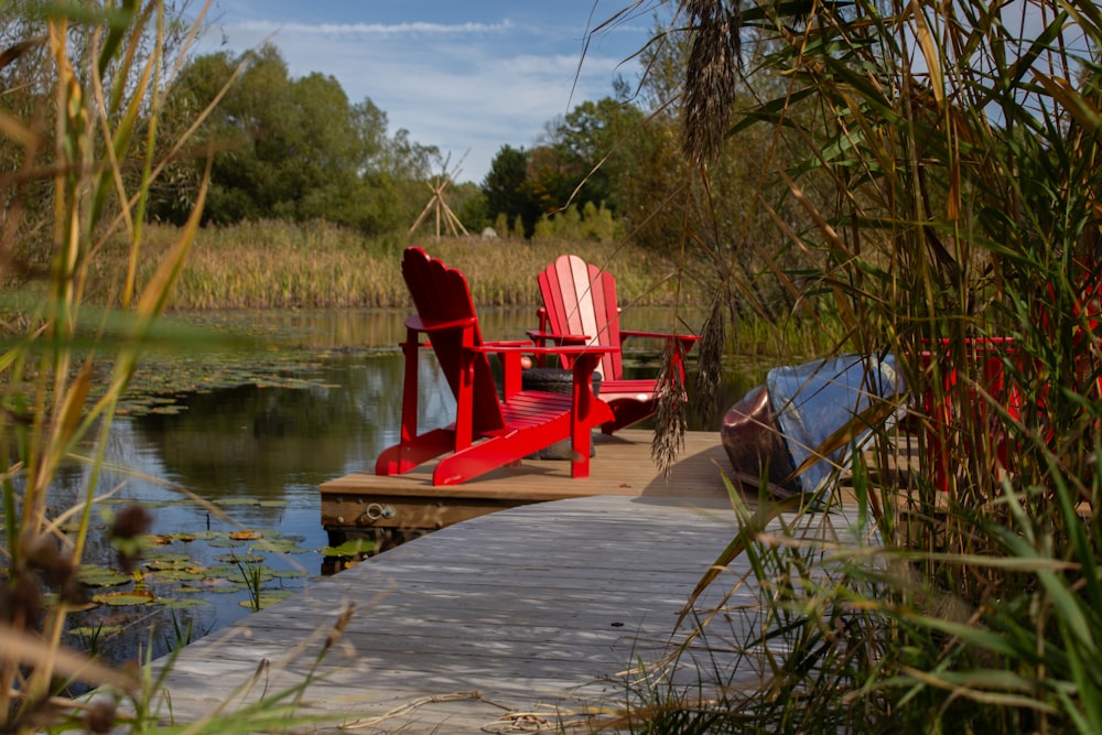 une chaise rouge assise sur un quai à côté d’un plan d’eau