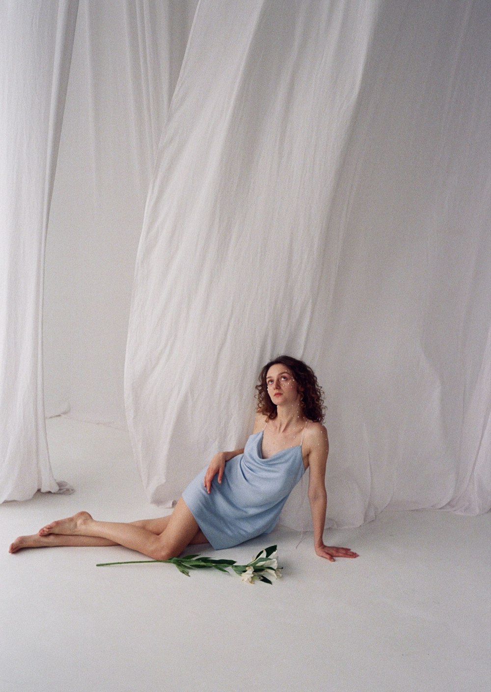 a woman in a blue dress sitting on the floor