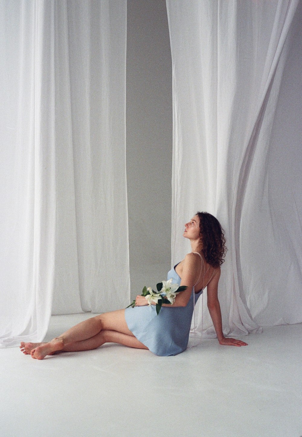 a woman sitting on the floor in front of a curtain