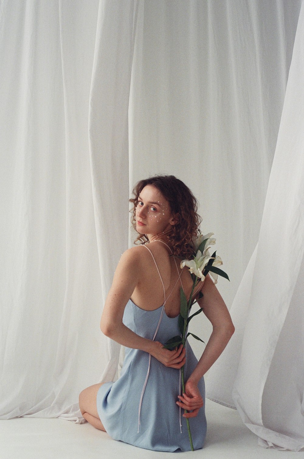 a woman sitting on the floor with a flower in her hand