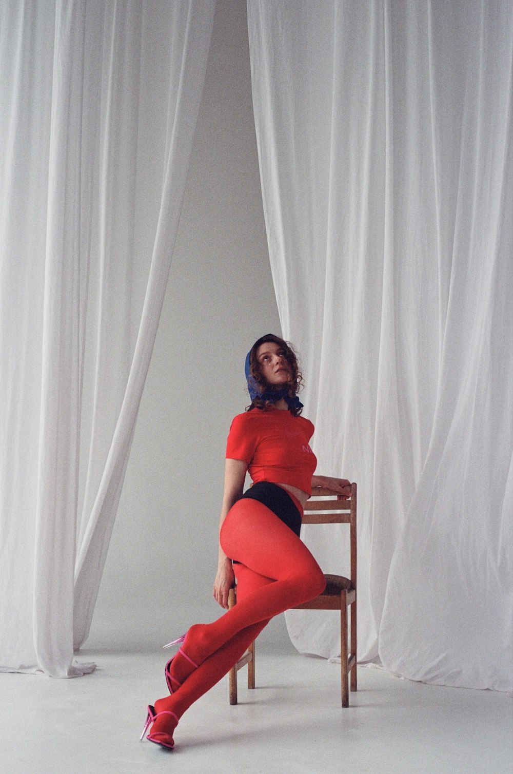 a woman sitting on a chair in front of a curtain