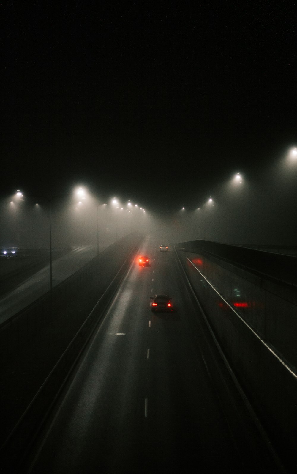 a foggy night on a highway with cars driving down it