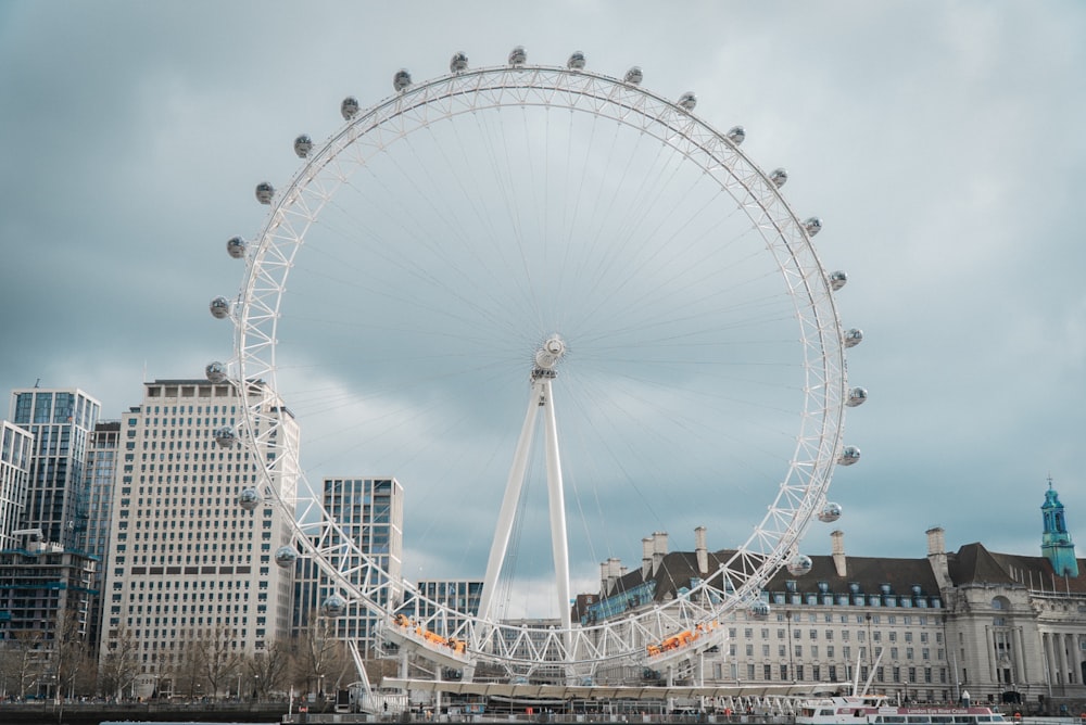 a large white ferris wheel in front of a city