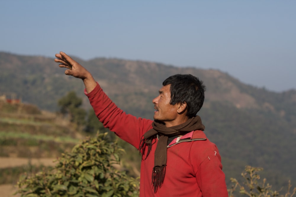 a man in a red shirt is pointing at something