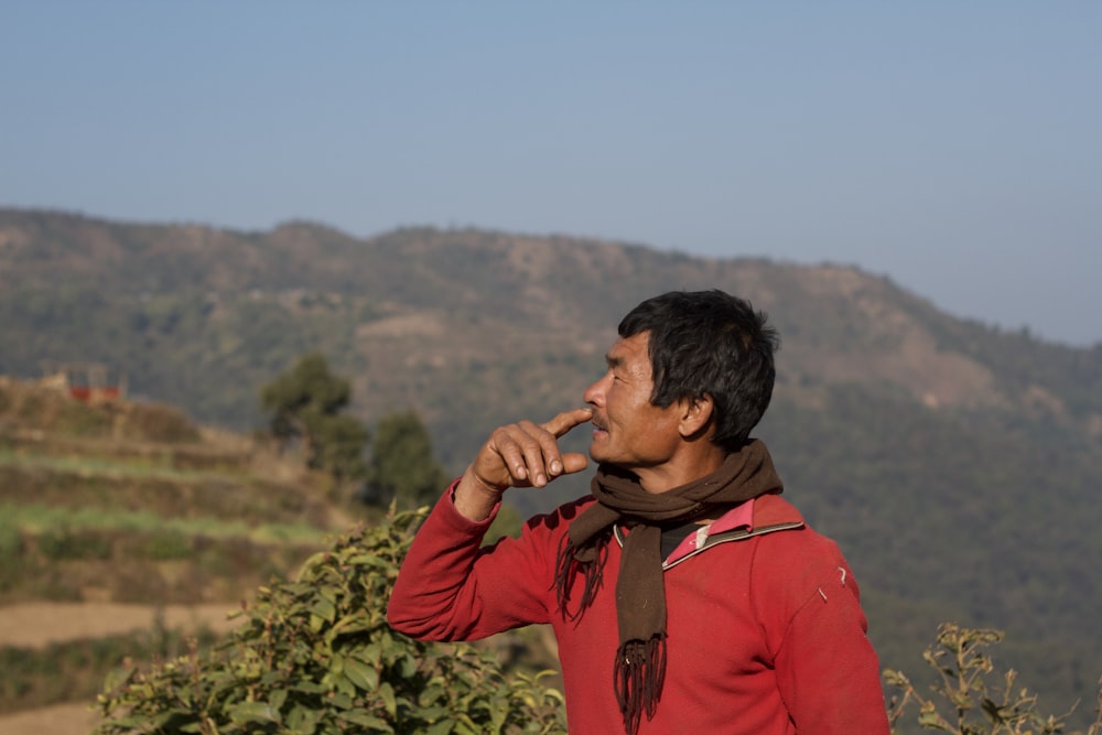 a man standing in front of a mountain with a scarf around his neck