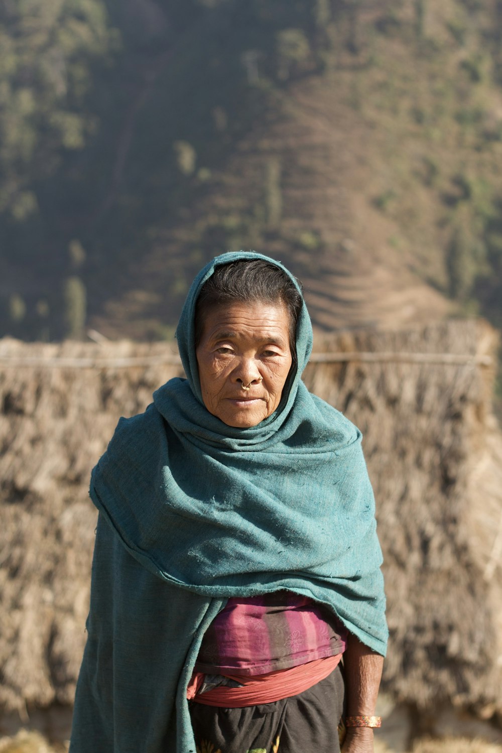 a woman with a green shawl standing in front of a mountain