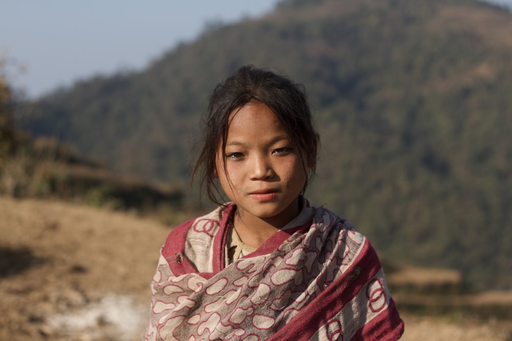 a young girl standing in front of a mountain