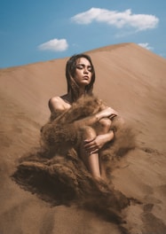a woman sitting on top of a sandy hill