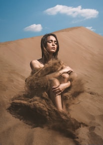 a woman sitting on top of a sandy hill