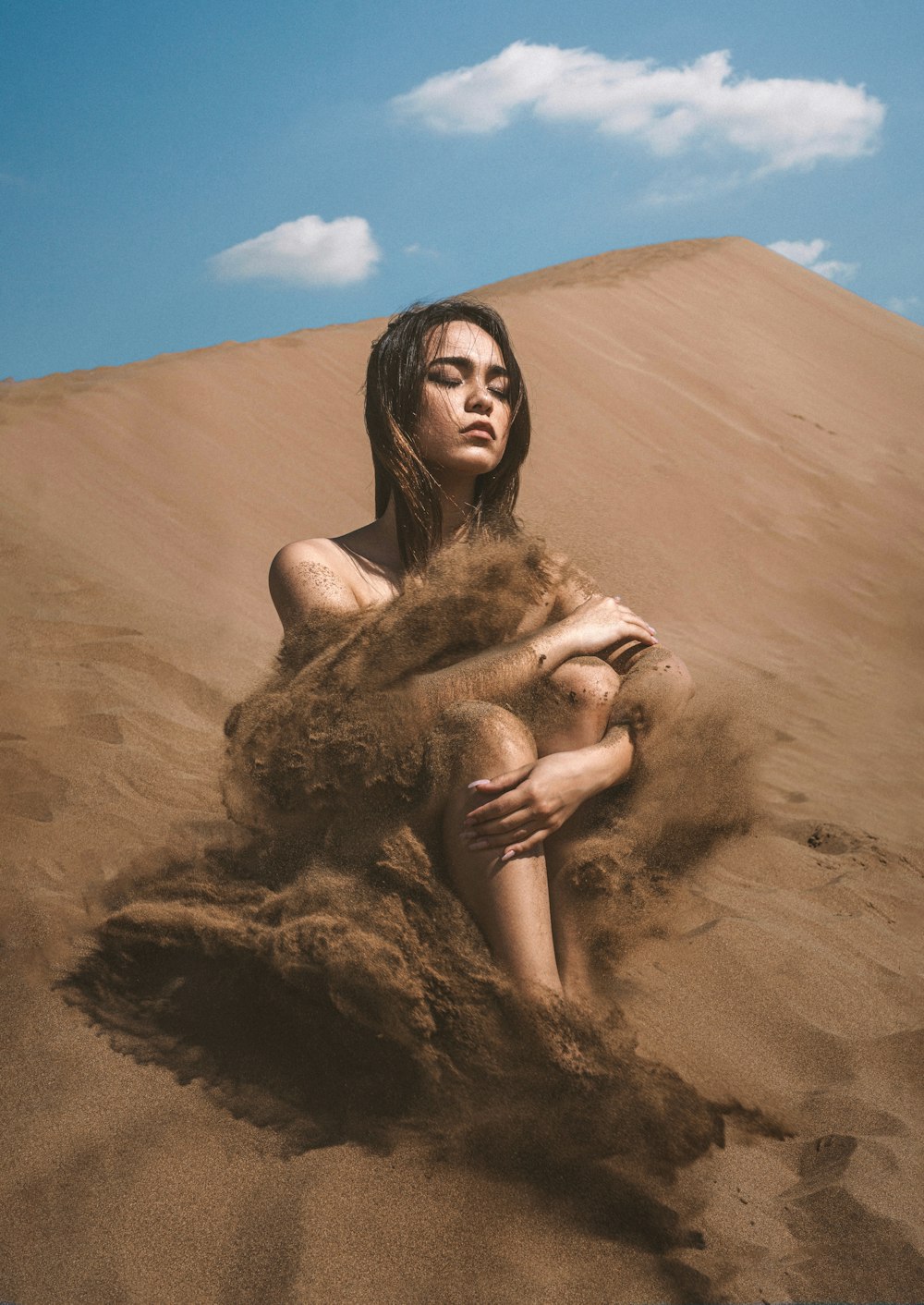 a woman sitting on top of a sandy hill