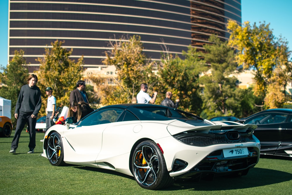 a group of people standing around a white sports car