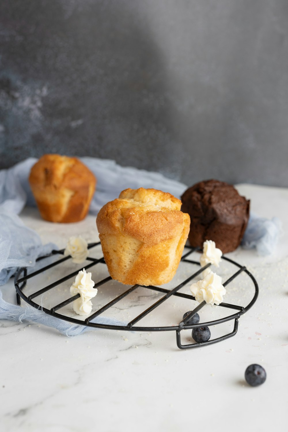 three muffins sitting on a wire rack on a counter