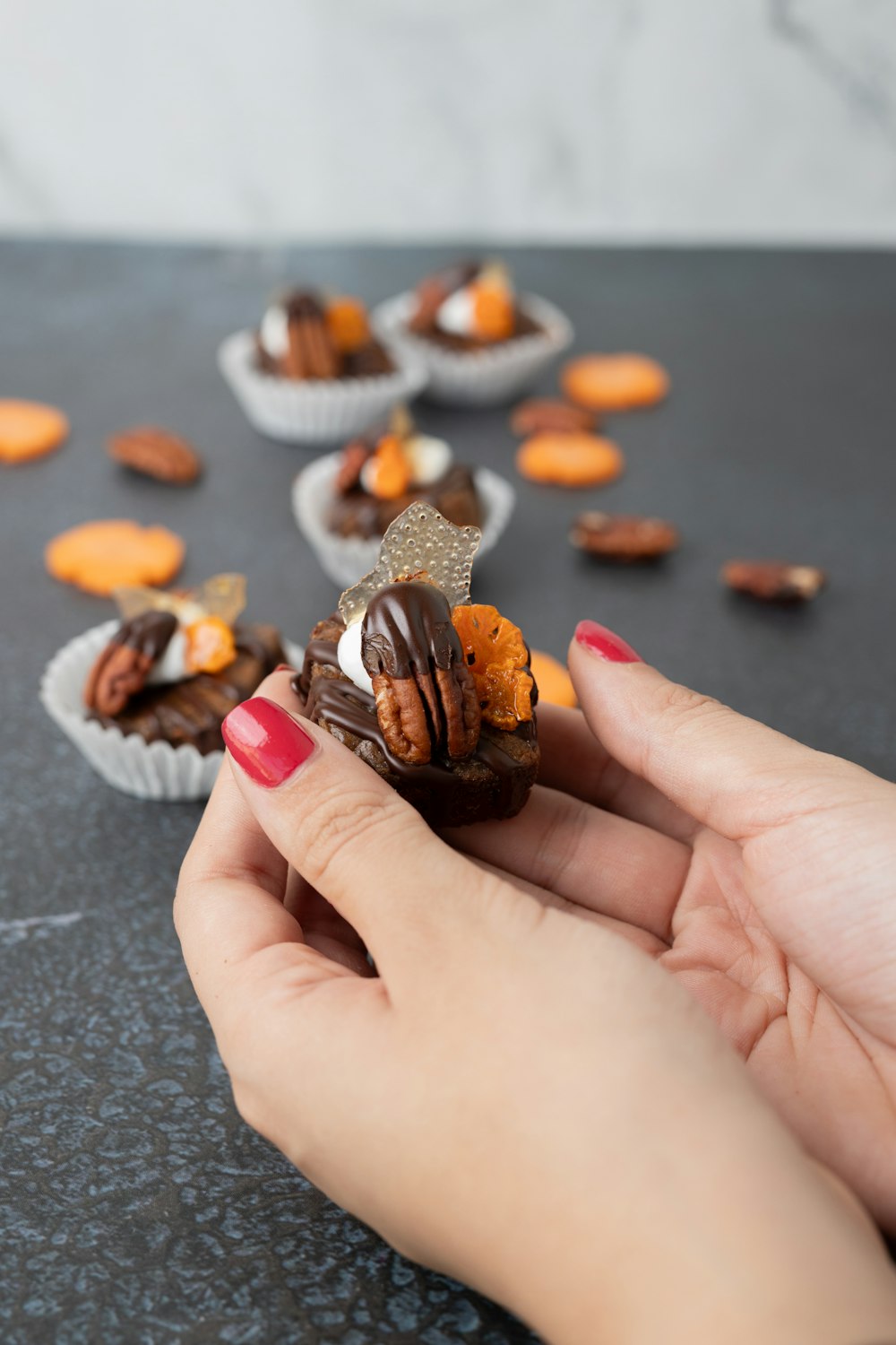 a hand holding a piece of chocolate covered in nuts