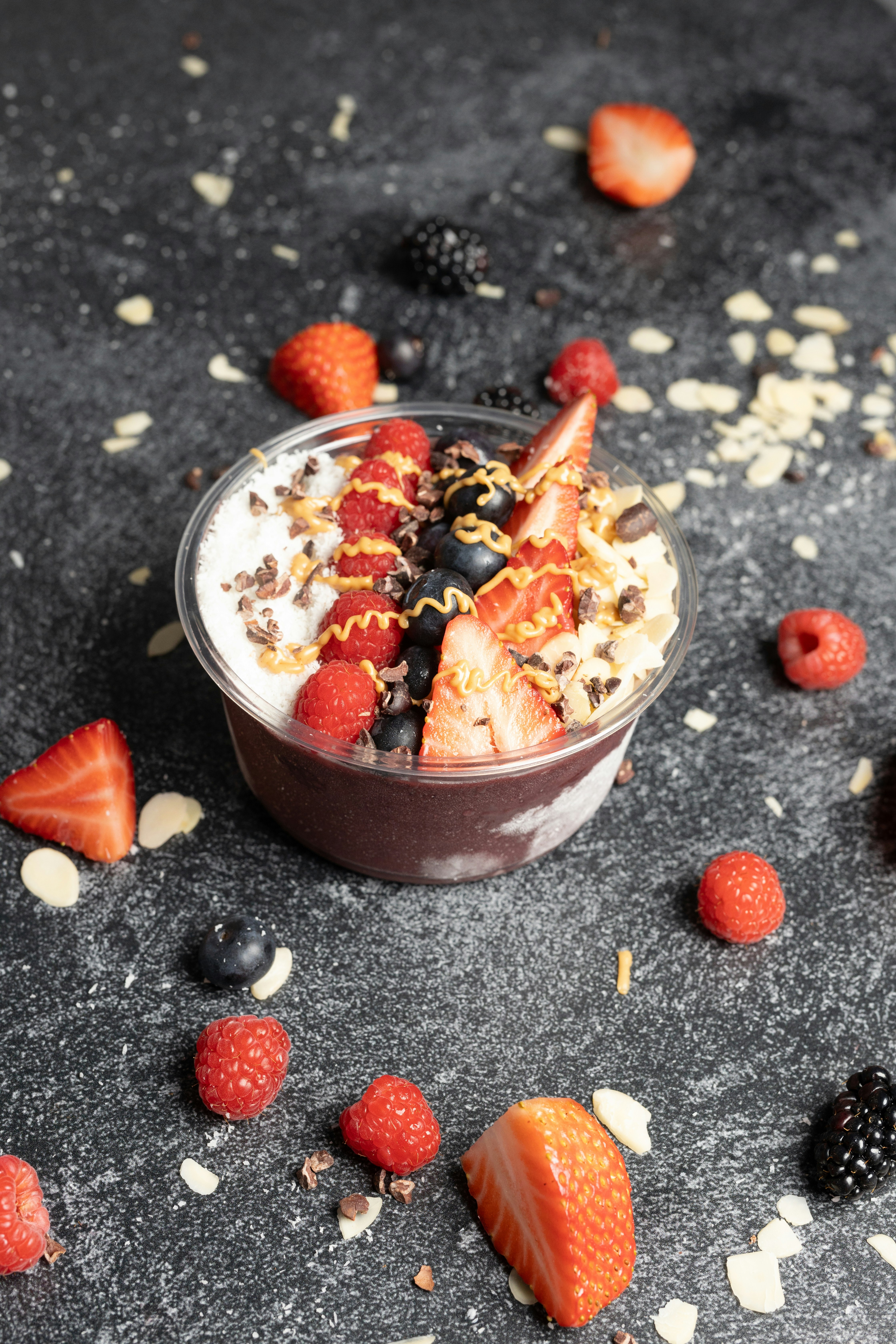 a dessert in a bowl with strawberries and berries around it