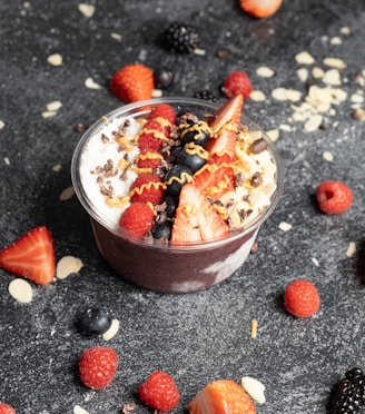 a dessert in a bowl with strawberries and berries around it