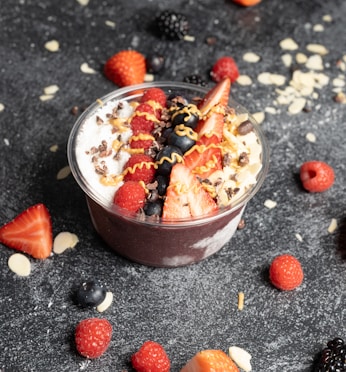 a dessert in a bowl with strawberries and berries around it