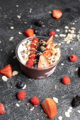 a dessert in a bowl with strawberries and berries around it