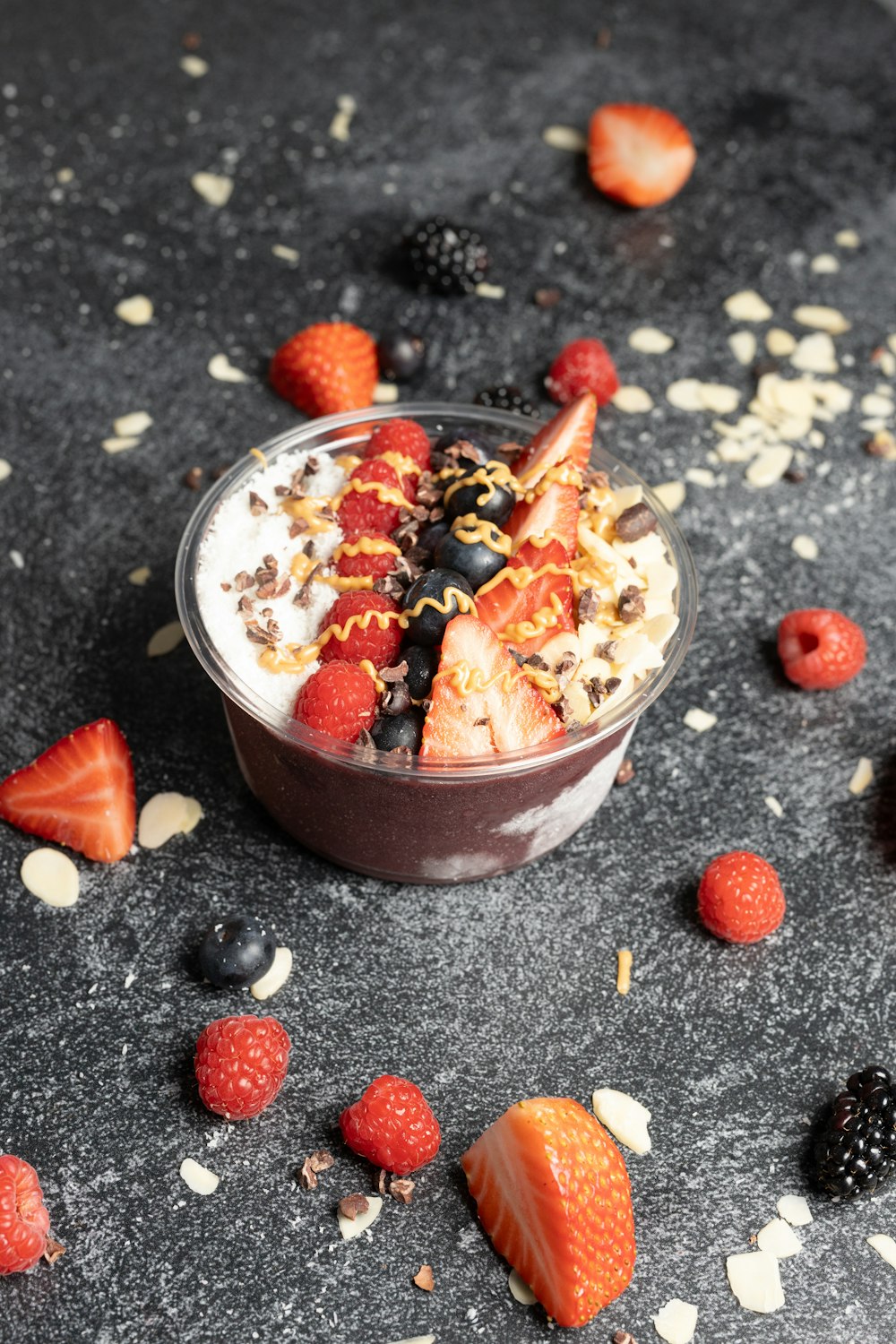 a dessert in a bowl with strawberries and berries around it